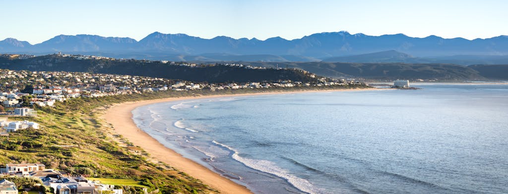 Breathtaking aerial view of Plettenberg Bay's coastline with mountains and seaside homes.