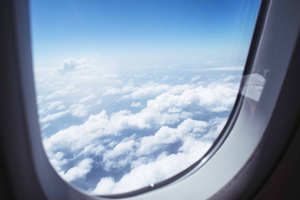 Breathtaking view of clouds and blue sky through an airplane window during flight.