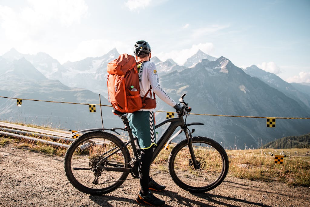 Cyclist with backpack enjoying a scenic mountain view in Saas-Fee, Switzerland.