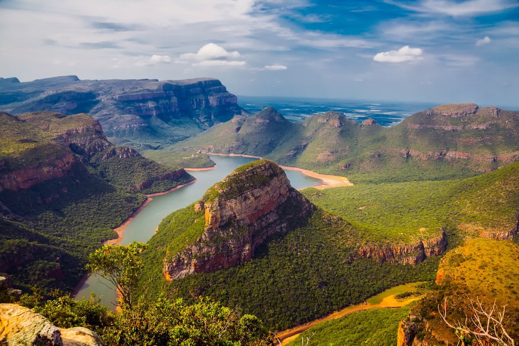 Explore the breathtaking vistas of Blyde River Canyon with dramatic cliffs and lush greenery.