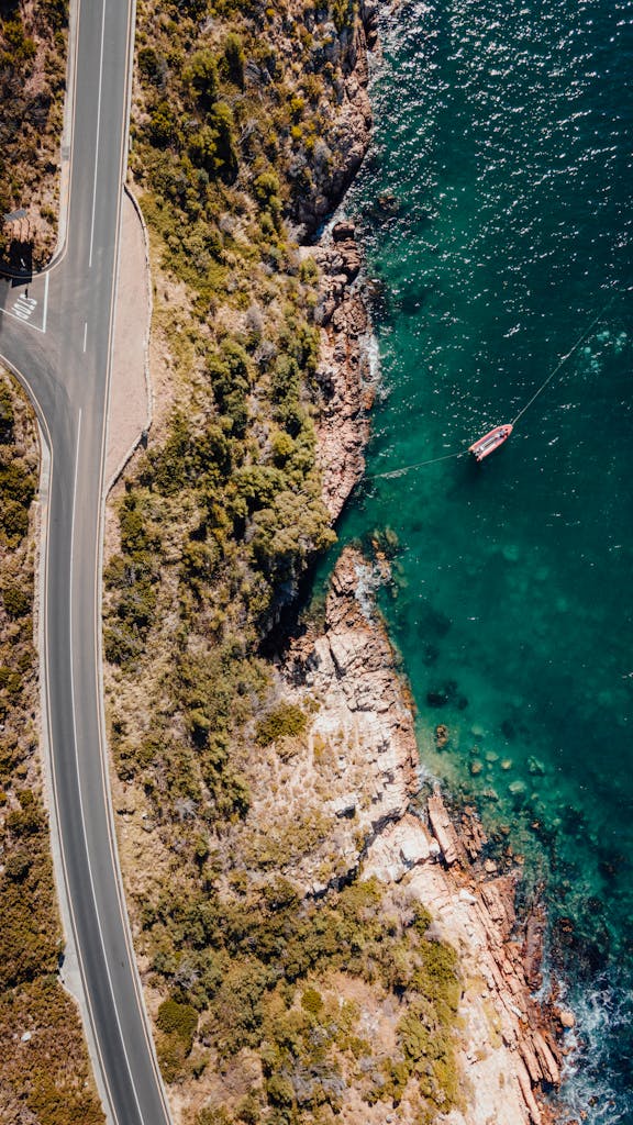 Stunning aerial view of a winding coastal road and boat in South Africa.