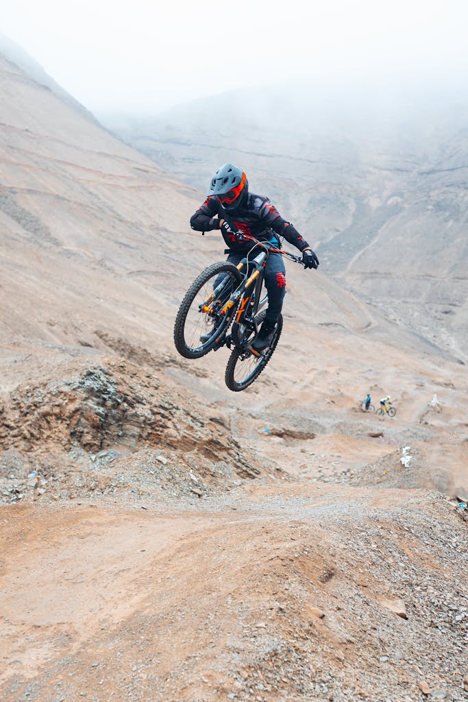 Thrilling mountain biking jump captured in barren desert terrain, showcasing adventure and skill.