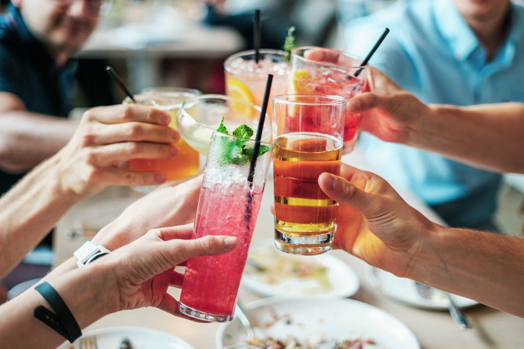 Friends enjoying a toast with vibrant cocktails at an indoor gathering.