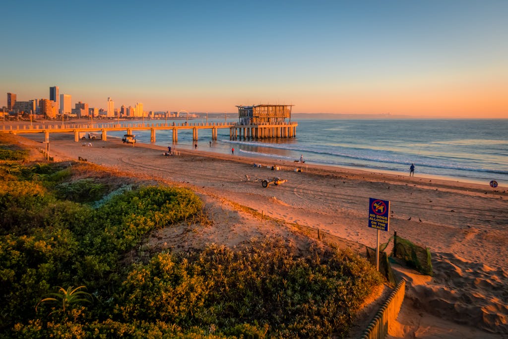 Golden sunrise over Durban's beachfront with a pier extending into the ocean. Perfect coastal view.