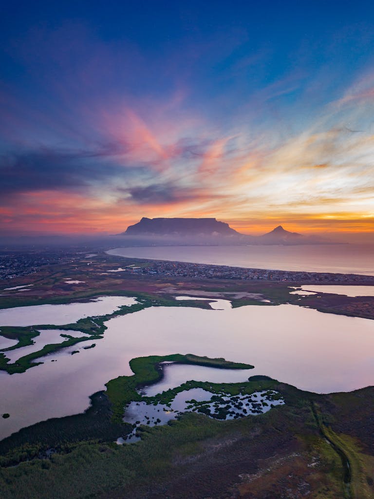 Stunning aerial view of Table Mountain with vibrant sunset skies and serene landscapes.