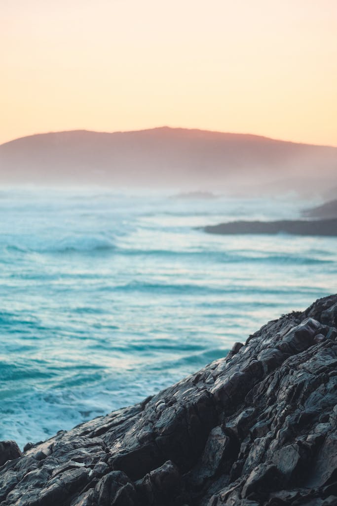 A stunning view of waves crashing against rocks at sunset along the South African coast.