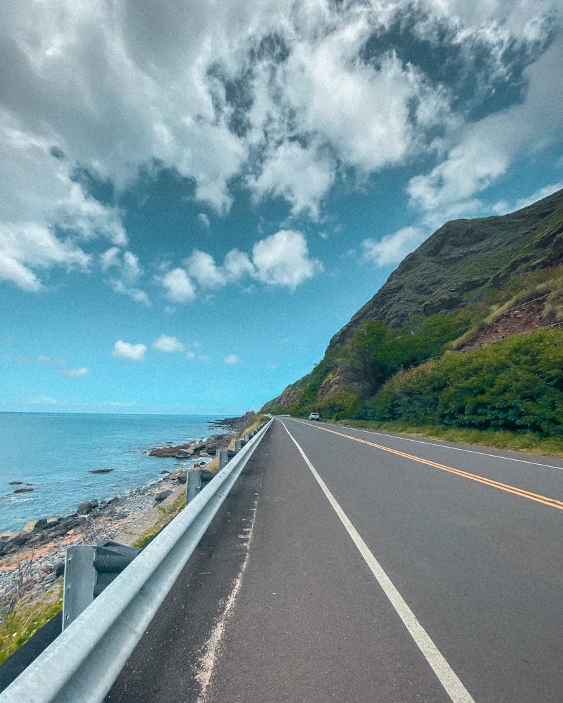 A tranquil coastal road with lush greenery and ocean view in Hawaii, perfect for serene road trips.