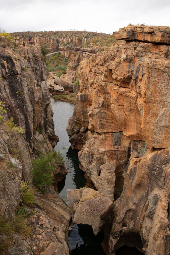 A breathtaking view of a bridge spanning a rocky canyon with a river flowing below, showcasing natural beauty.
