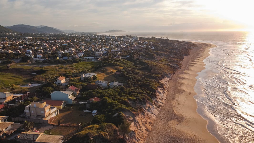 Aerial photograph of a coastal town in Brazil with beach, houses, and ocean at sunrise.