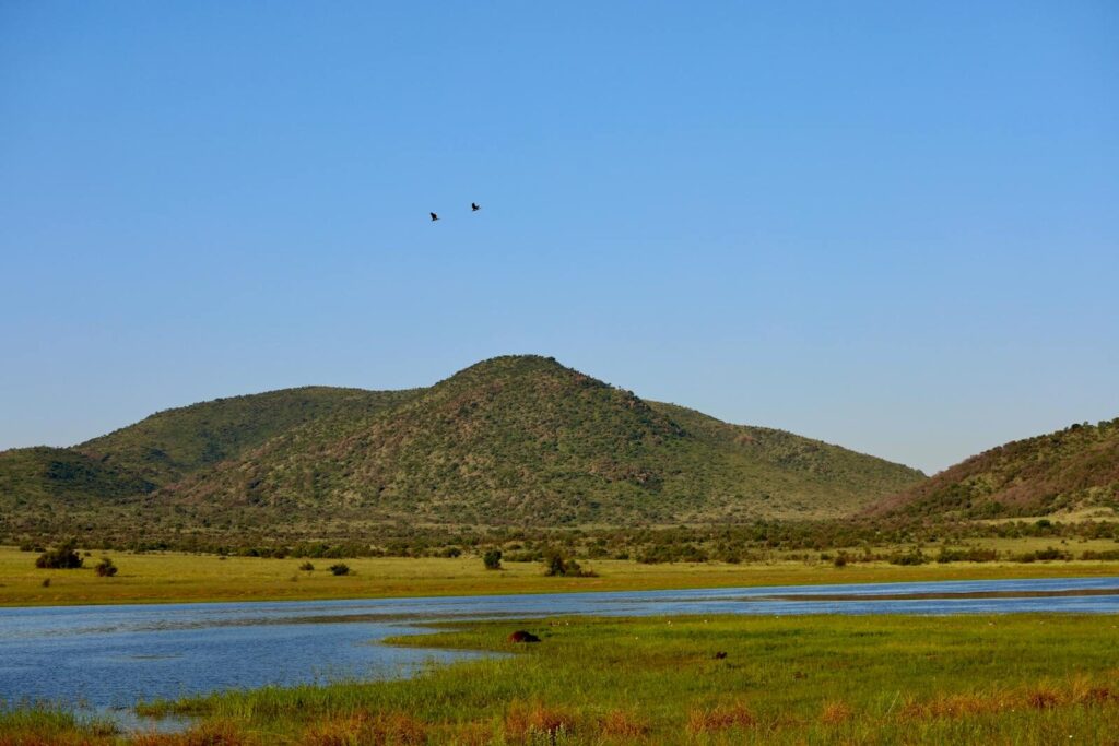 Serene view of hills and a river under a clear blue sky.