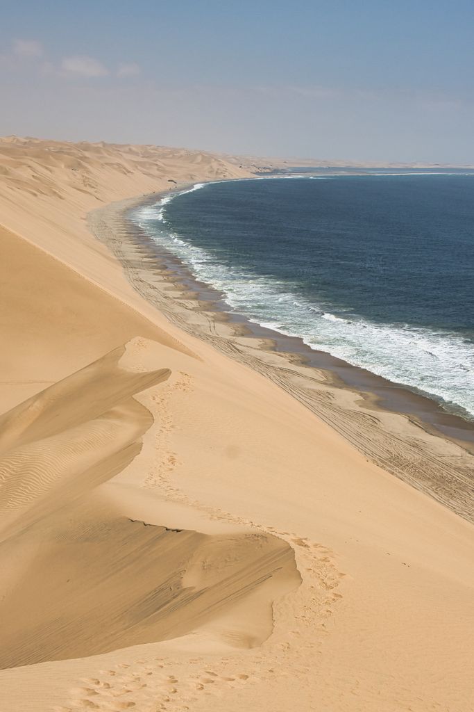 Capture the breathtaking view of Namib Desert dunes merging with the Atlantic Ocean.