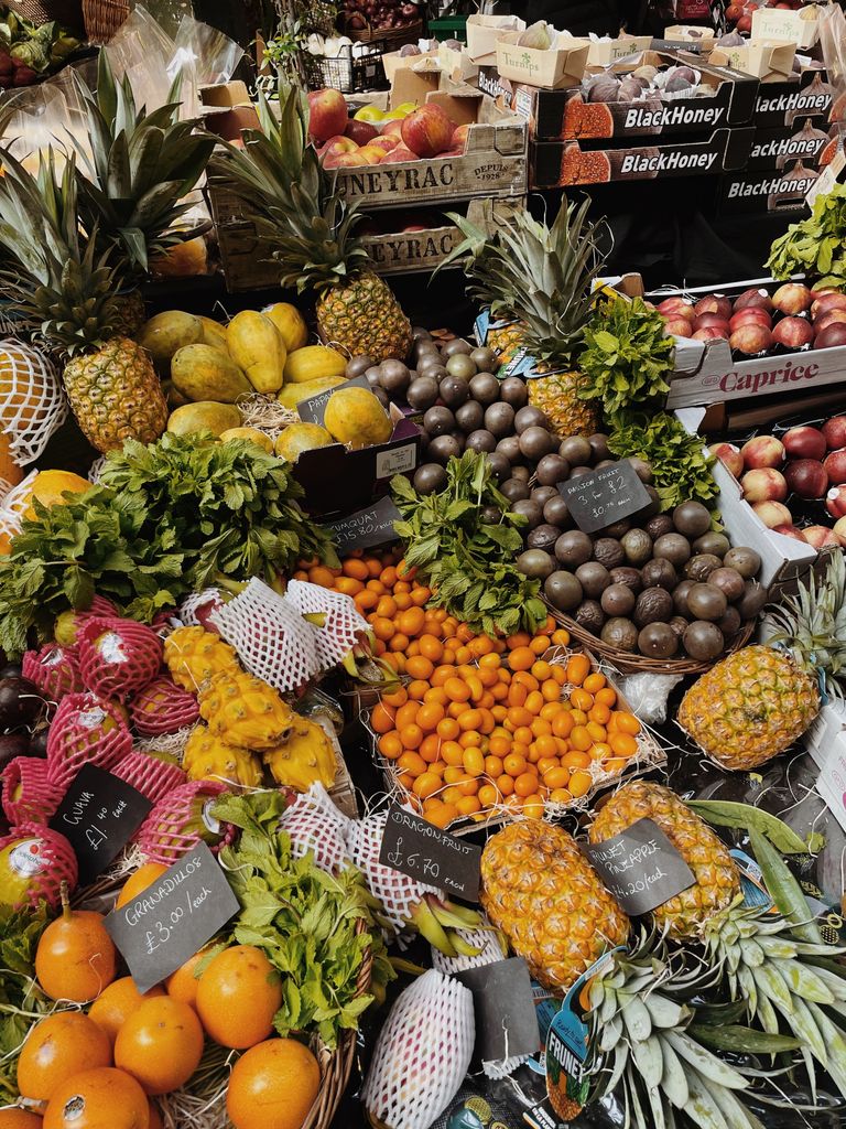 A colorful display of tropical fruits at a market stall, including pineapples, oranges, and more.