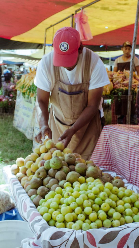 A vendor arranging fresh produce at a vibrant outdoor market in Cholula, Mexico.